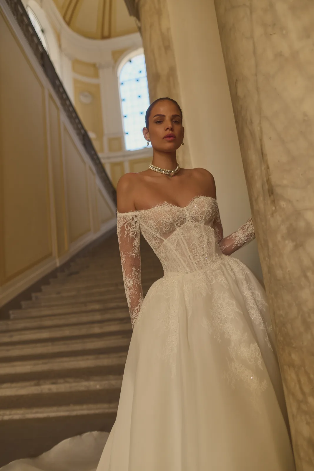 Versione principessa dell’abito da sposa Essentia con maniche in pizzo off-shoulder